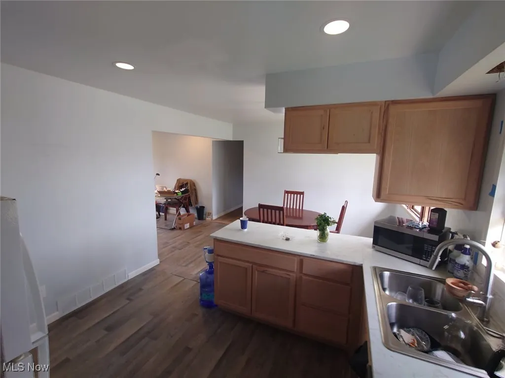 Kitchen featuring light countertops, dark wood-type flooring, recessed lighting, stainless steel microwave, and a peninsula