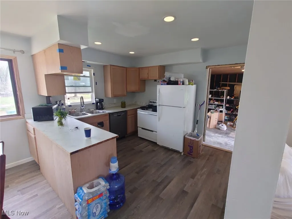 Kitchen with light countertops, white appliances, light brown cabinetry, dark wood finished floors, and recessed lighting