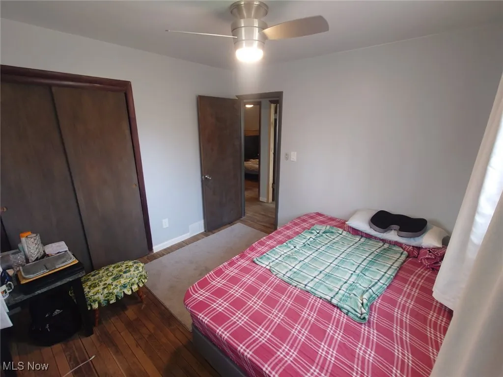 Bedroom featuring dark wood-style flooring, a closet, and a ceiling fan