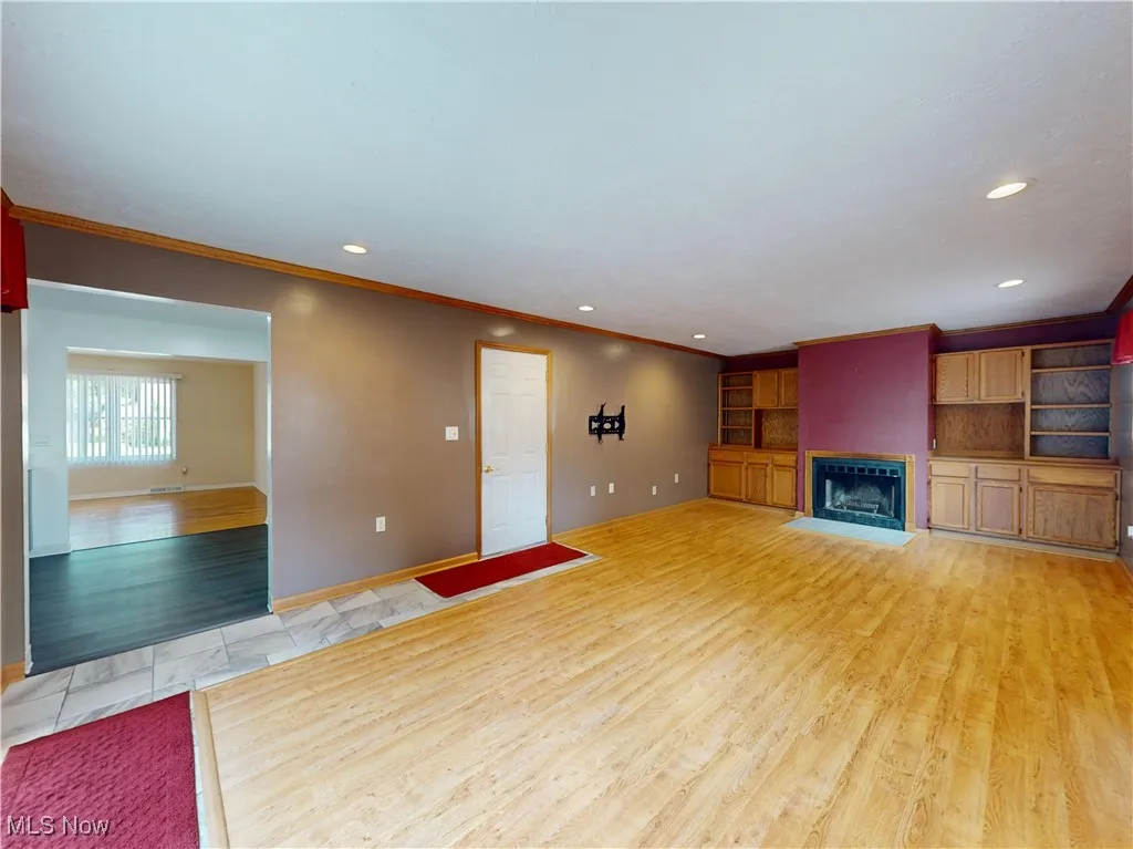Unfurnished living room featuring light wood-type flooring, ornamental molding, recessed lighting, and a fireplace