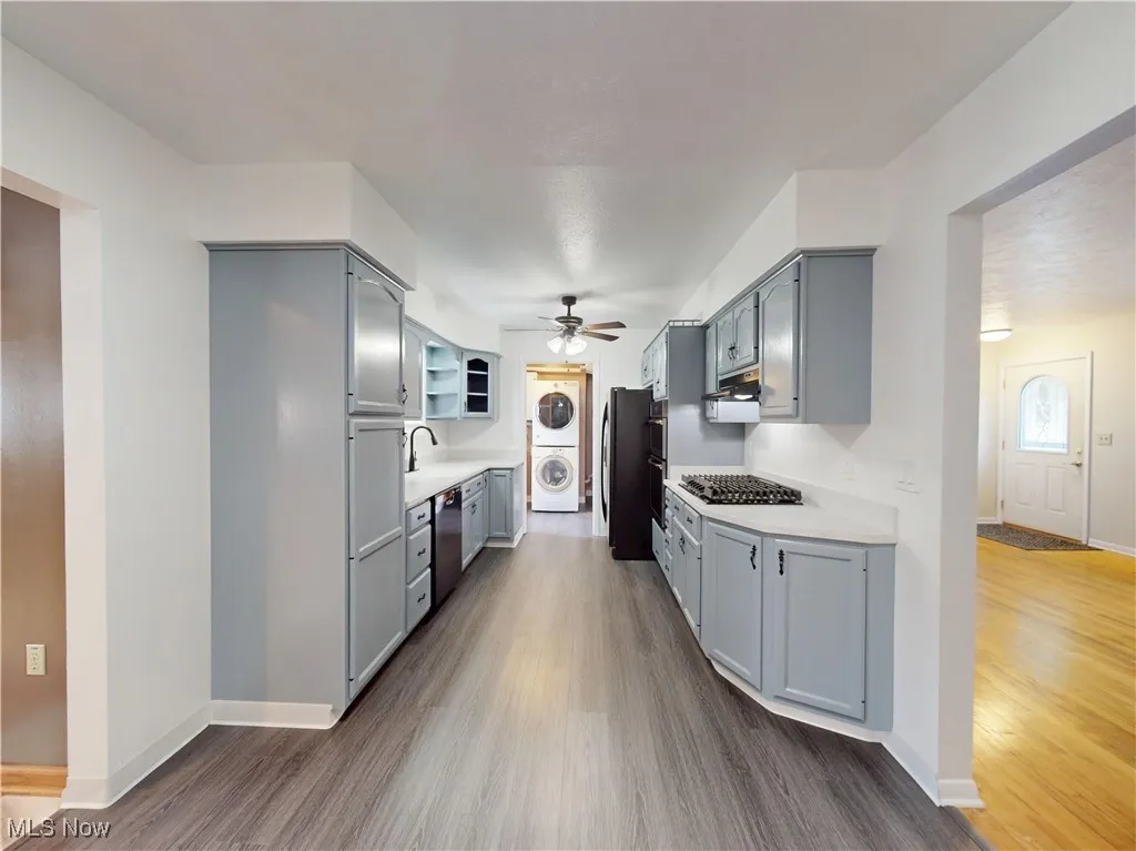 Kitchen featuring estacked washer and dryer, gray cabinetry, dark wood-style flooring, and light countertops