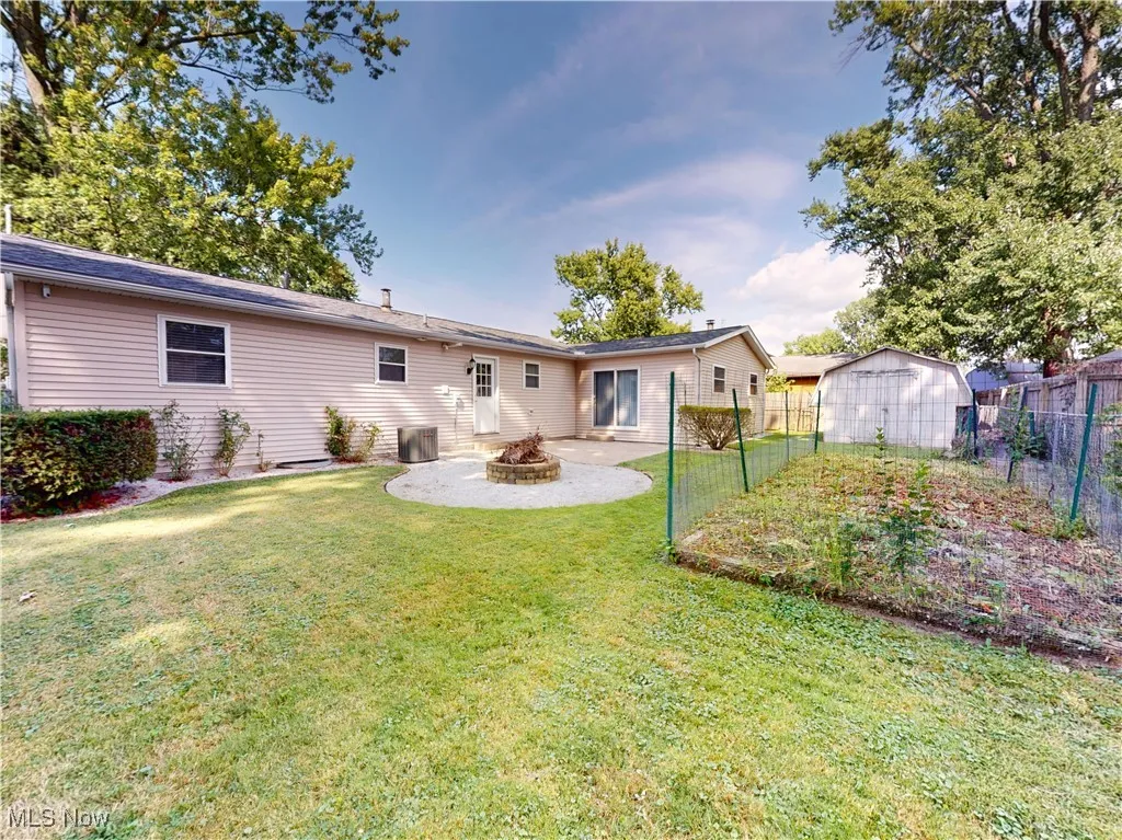 Rear view of property featuring an outdoor fire pit, a fenced backyard, a shed, and a patio area