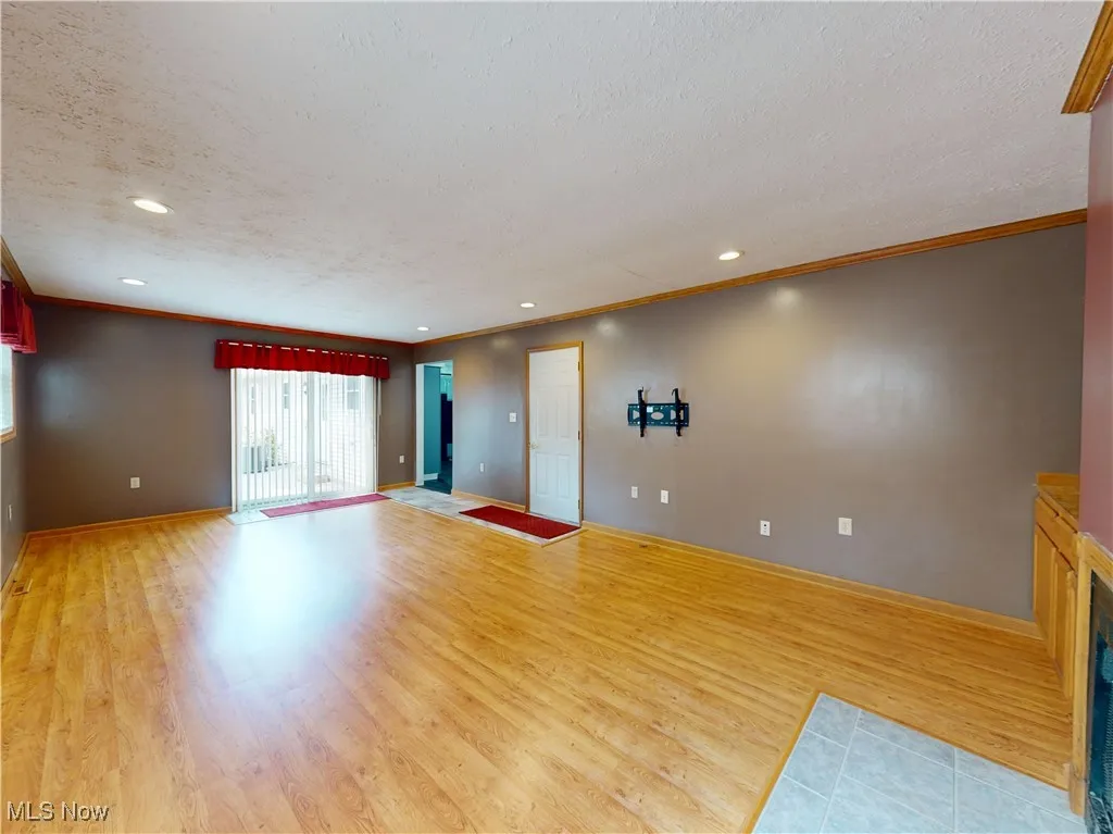 Unfurnished living room featuring crown molding, wood finished floors, recessed lighting, and a textured ceiling