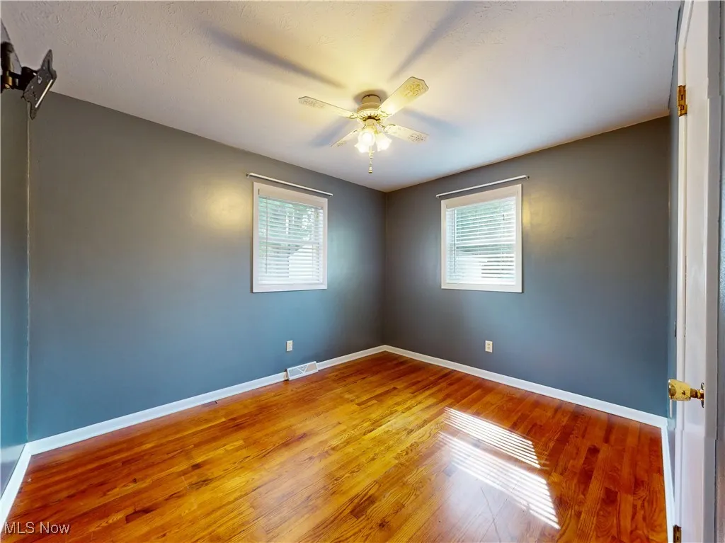 Bedroom with wood finished floors, healthy amount of natural light, and a ceiling fan