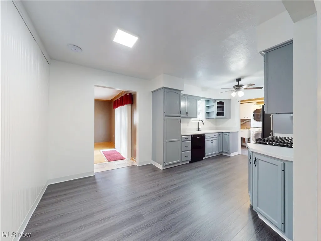 Dining room with gray cabinetry, dark wood-type flooring, light countertops, ceiling fan, and dishwasher