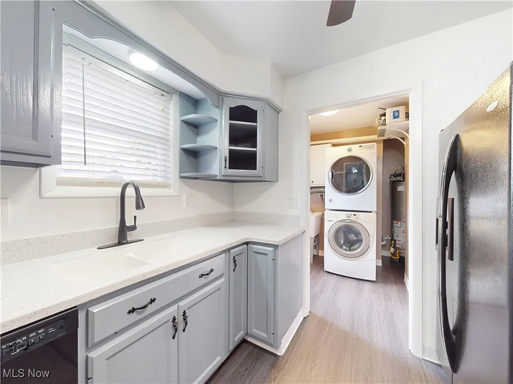 Laundry room featuring estacked washer and dryer, light wood-style floors, and a ceiling fan
