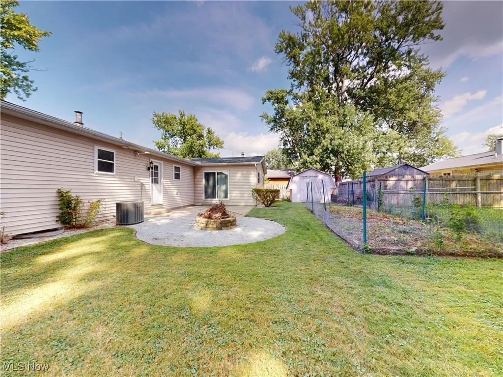 Back of house featuring a patio area, an outdoor fire pit, and an outbuilding