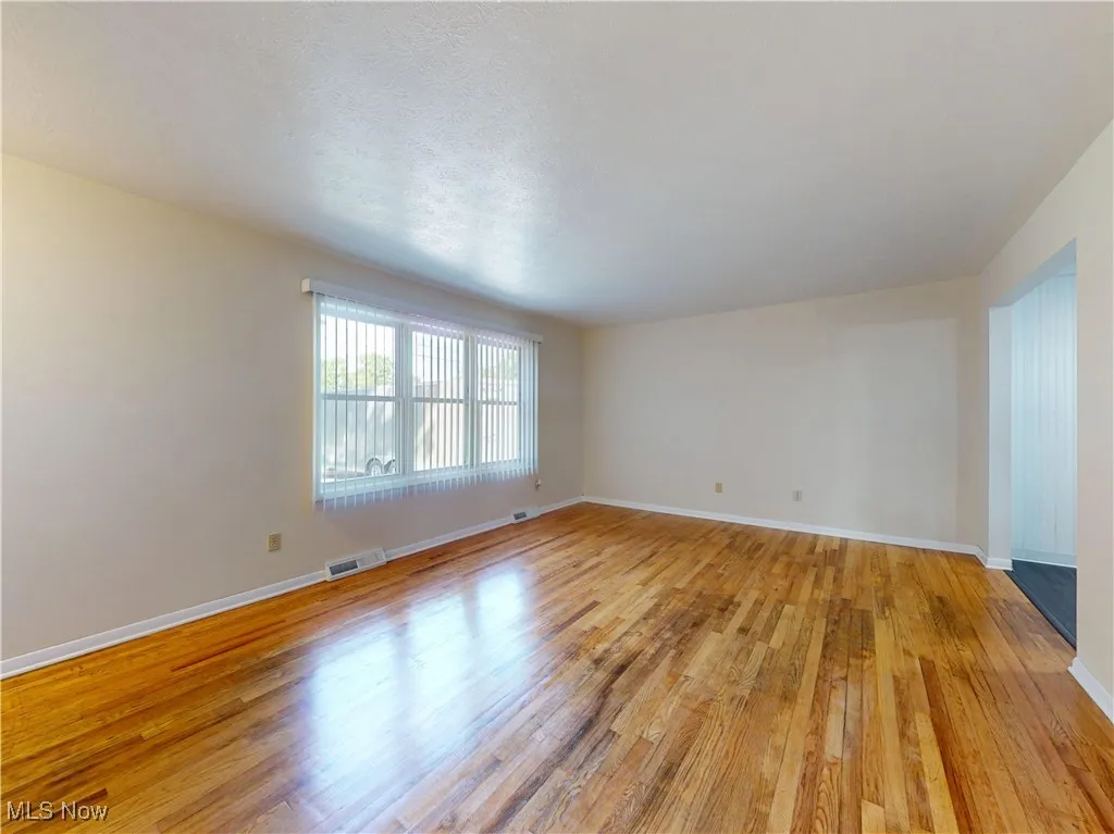 Empty room featuring light wood-type flooring and a textured ceiling