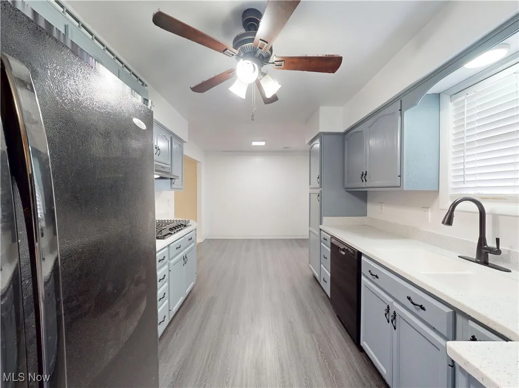 Kitchen with freestanding refrigerator, light wood-style flooring, gray cabinetry, ceiling fan, and black dishwasher