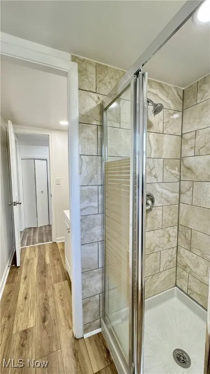 Bathroom with a stall shower, light wood-style floors, and vanity