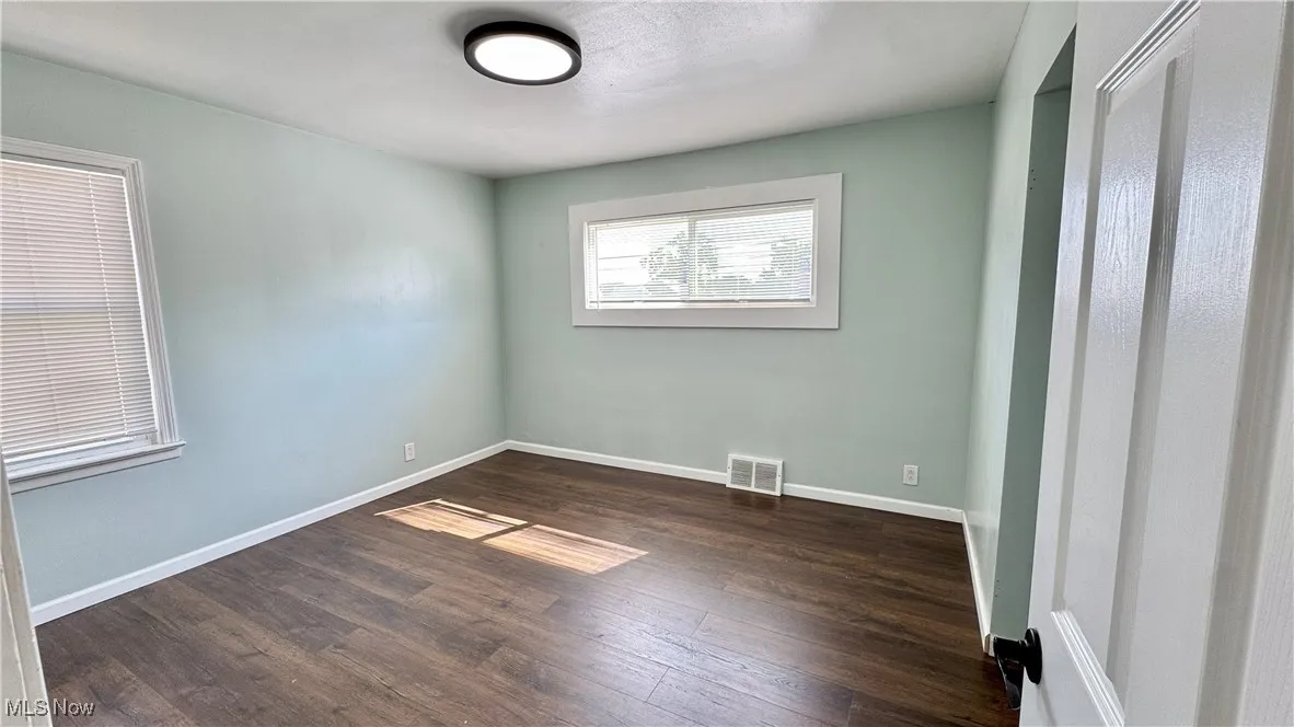 Unfurnished bedroom featuring dark wood-style flooring and baseboards