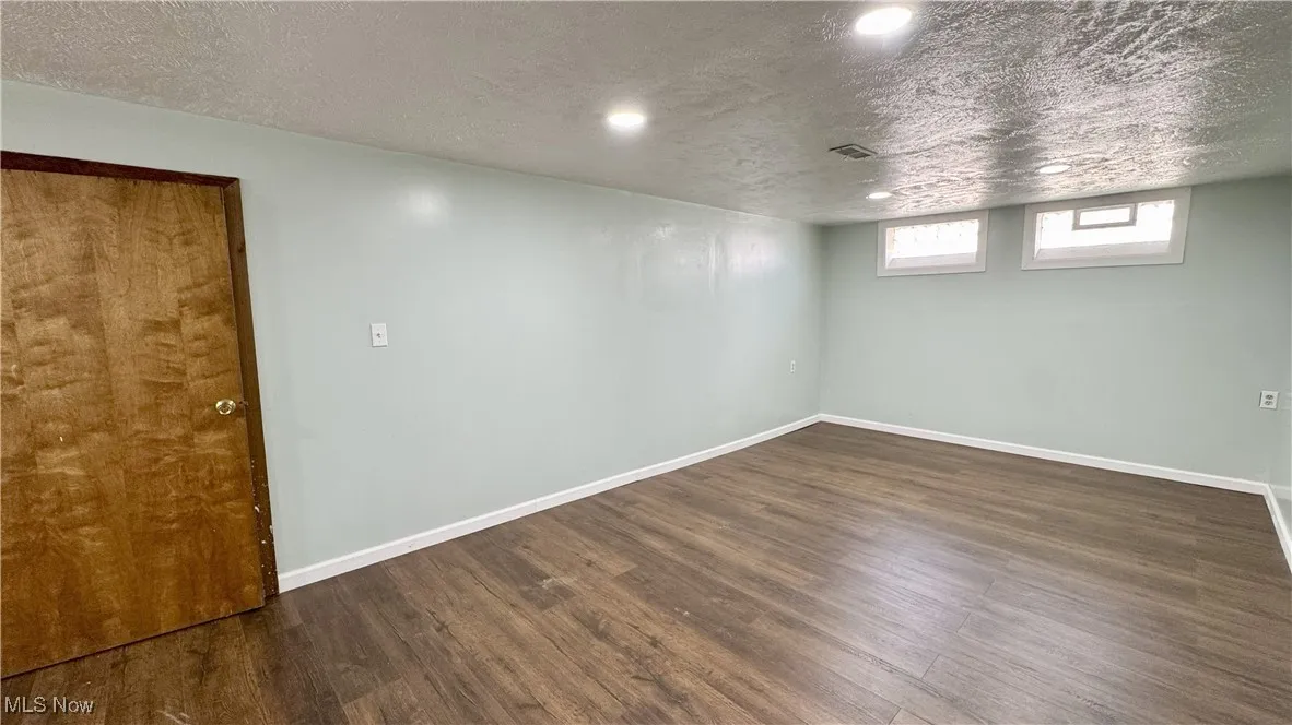 Below grade area with a textured ceiling, dark wood-style floors, and recessed lighting