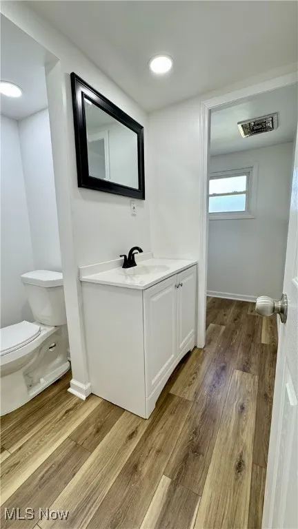 Half bathroom featuring light wood-type flooring, vanity, and recessed lighting