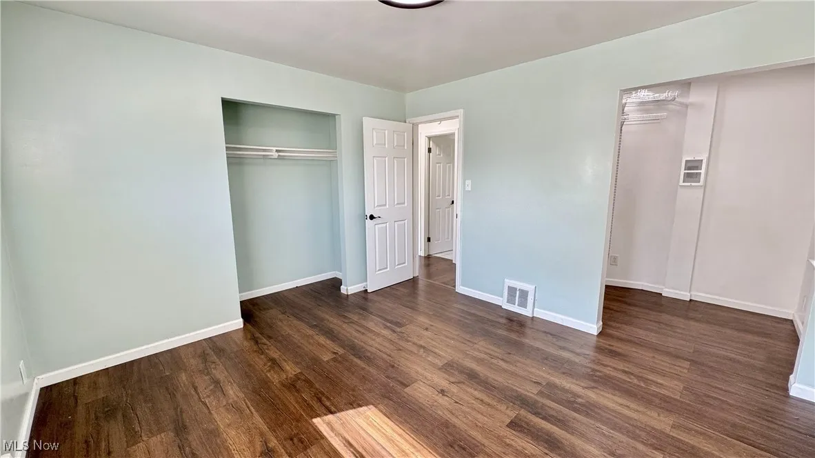Unfurnished bedroom with baseboards and dark wood finished floors