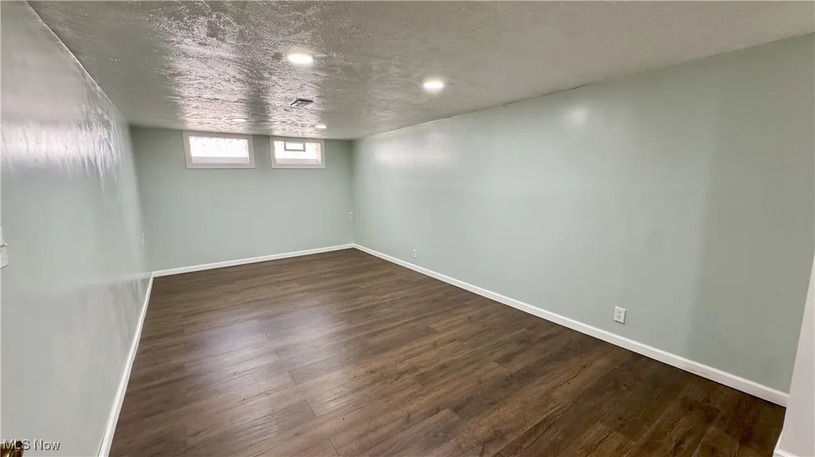Basement with dark wood-style flooring, a textured ceiling, and recessed lighting