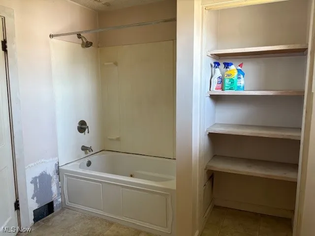Bathroom with tub / shower combination and light tile patterned floors