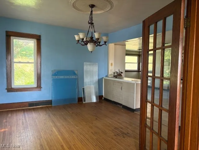 Dining area with dark wood-type flooring, plenty of natural light, and a chandelier