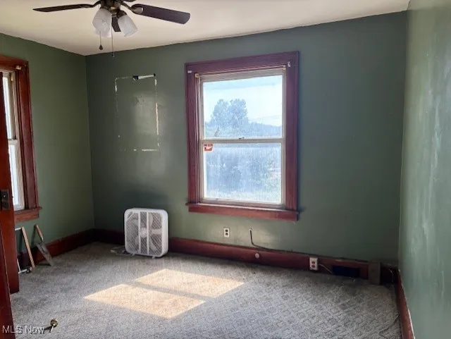 Carpeted empty room with baseboards and ceiling fan