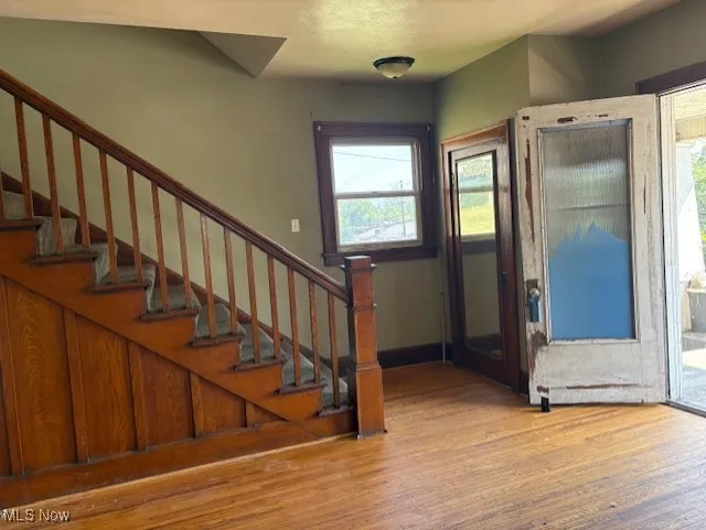 Foyer entrance featuring stairs, plenty of natural light, and light wood-style flooring
