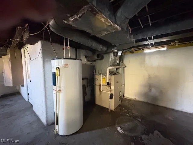 Unfinished below grade area featuring water heater and heating unit