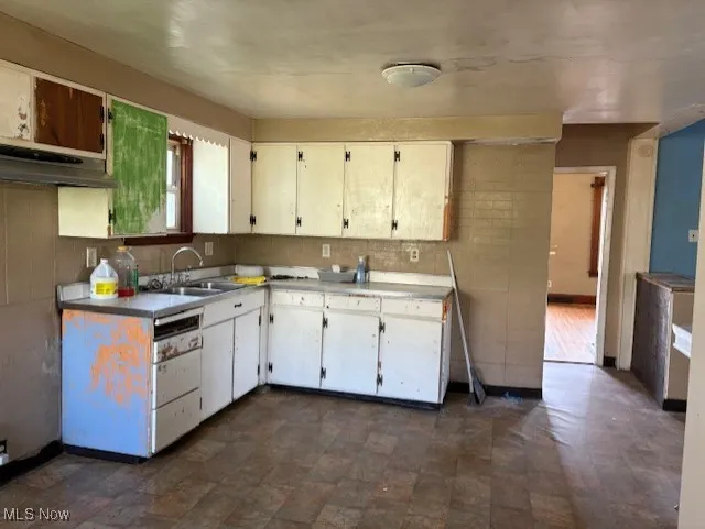 Kitchen featuring light countertops, white cabinets, and under cabinet range hood