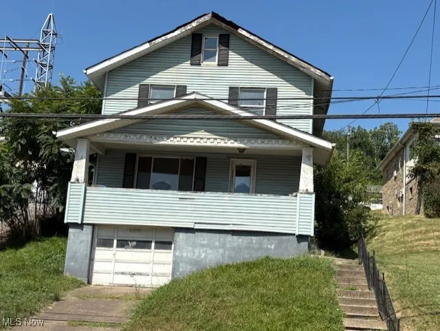 Traditional style home with stairs, an attached garage, a porch, and a front lawn