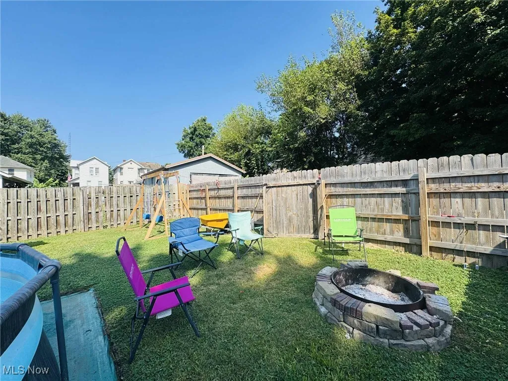 Fenced backyard with an outdoor fire pit and a playground