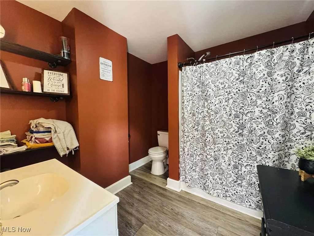 Full bath with vanity, light wood-type flooring, and curtained shower