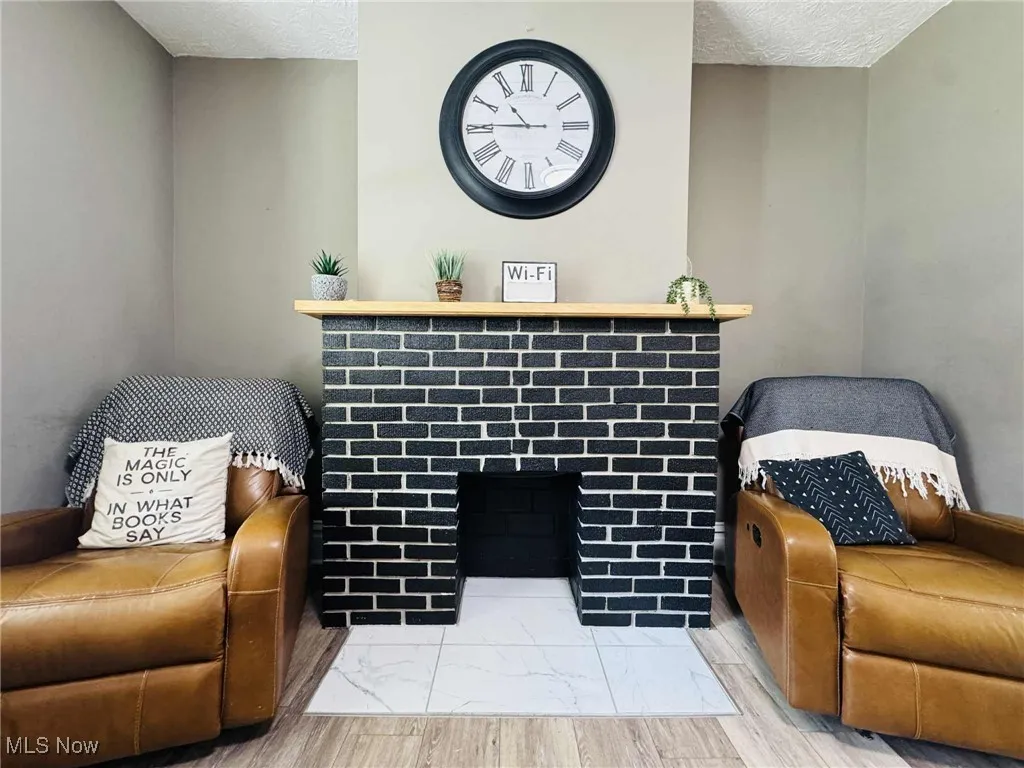 Sitting room with a textured ceiling, a fireplace, and wood finished floors