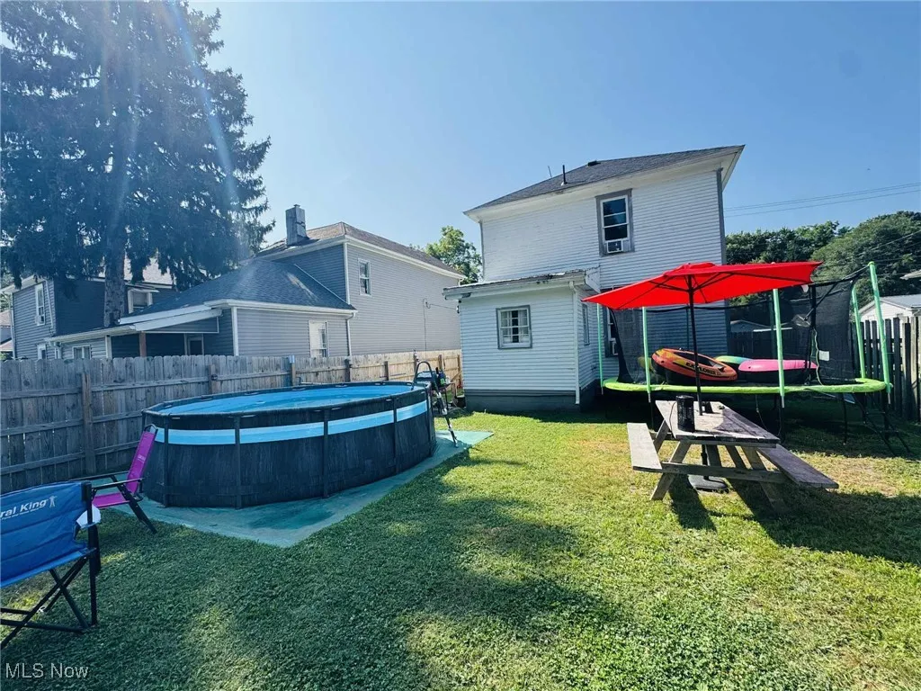 Back of house featuring a trampoline and a fenced backyard