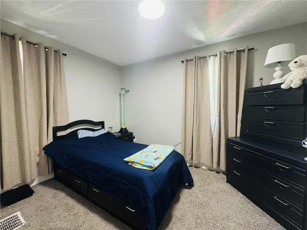 Bedroom with light carpet and a textured ceiling