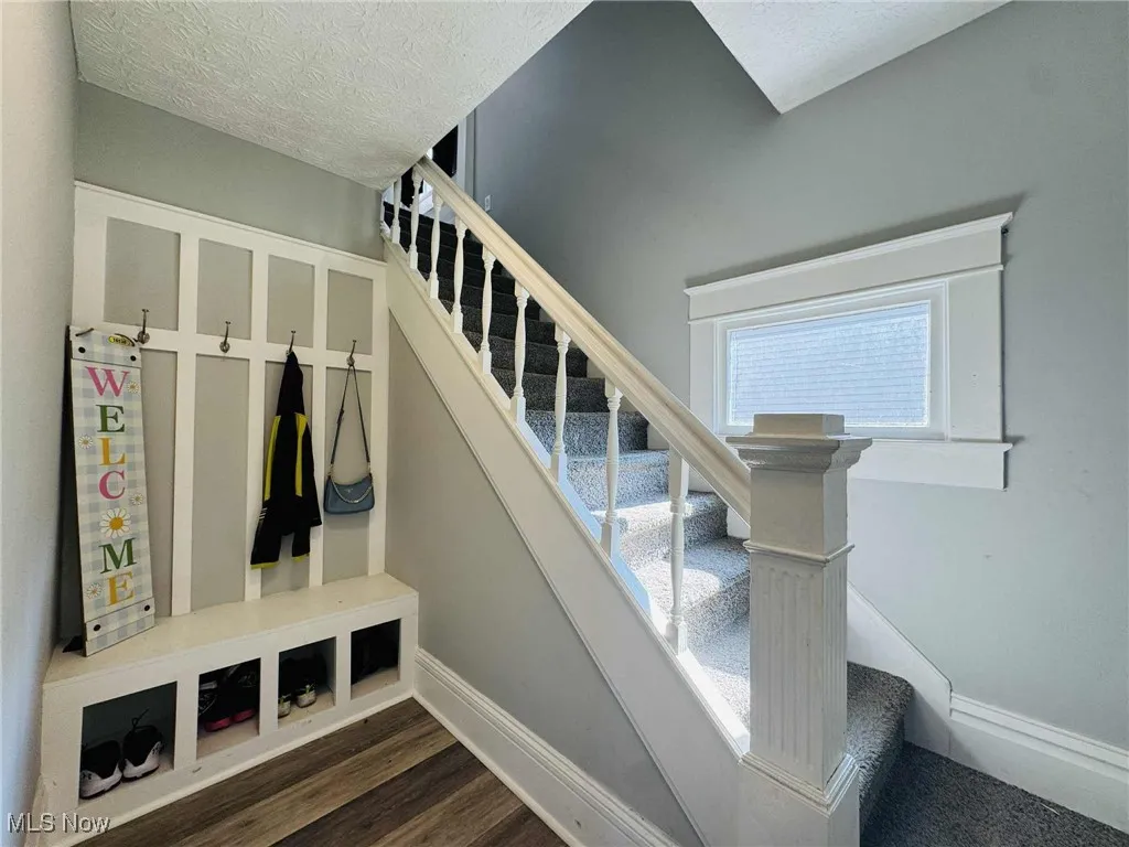 Stairs featuring wood finished floors and a textured ceiling