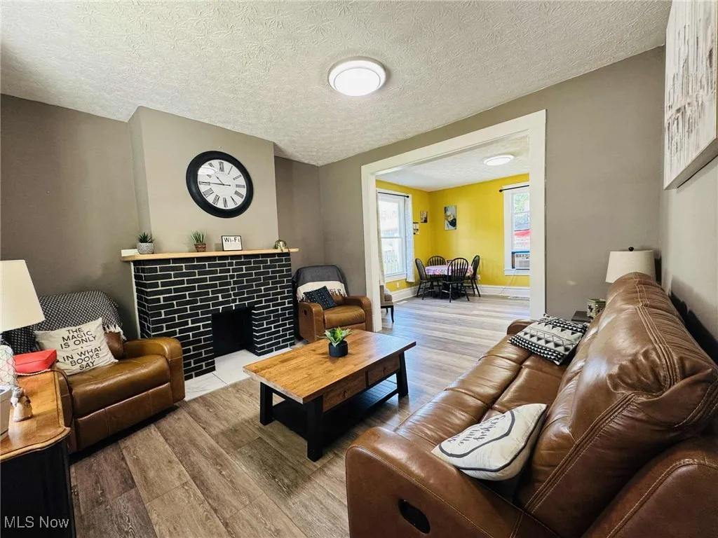 Living room featuring a textured ceiling, wood finished floors, and a tile fireplace