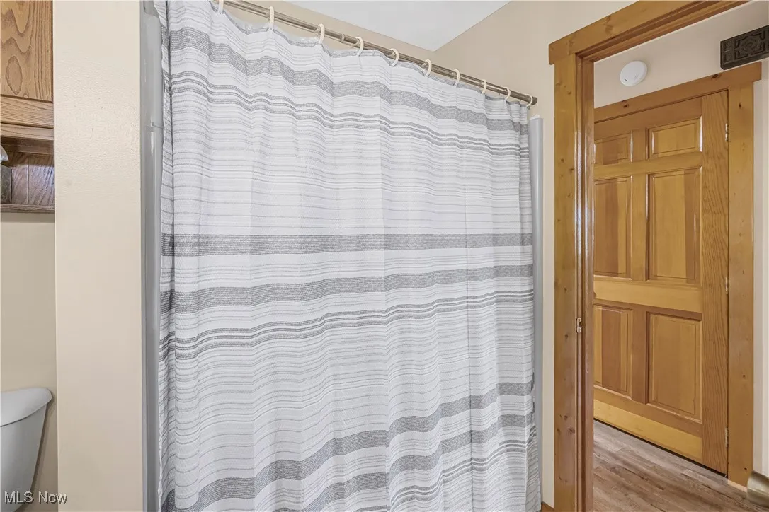 Full bathroom featuring wood finished floors and curtained shower
