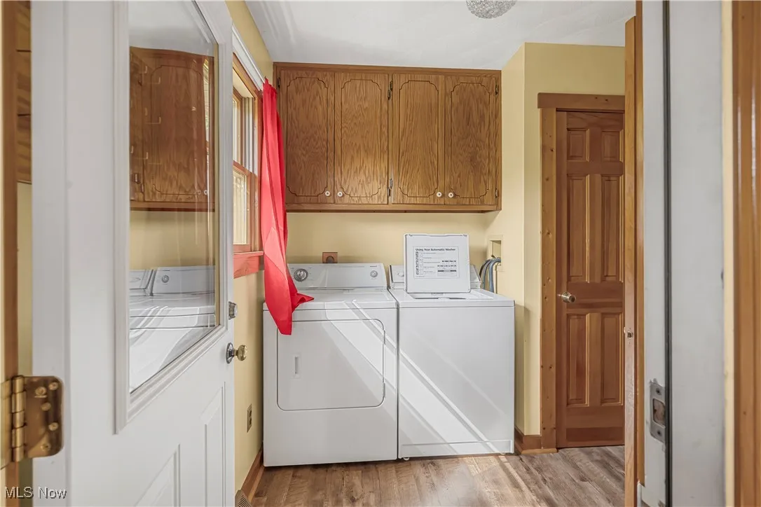 Laundry room featuring cabinet space, separate washer and dryer, and light wood finished floors