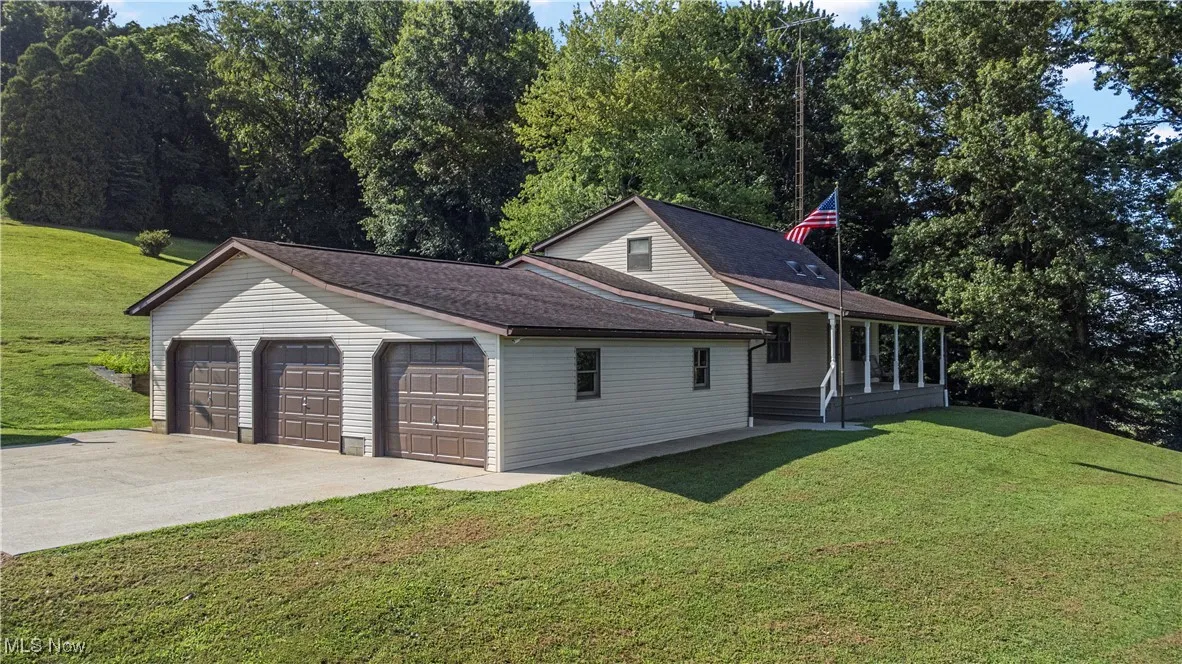 View of front of property featuring a front yard, a garage, roof with shingles, and driveway