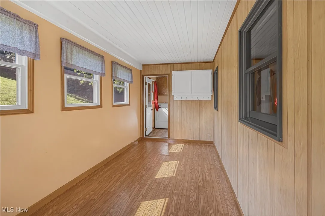 Corridor with light wood finished floors, wooden walls, and wood ceiling