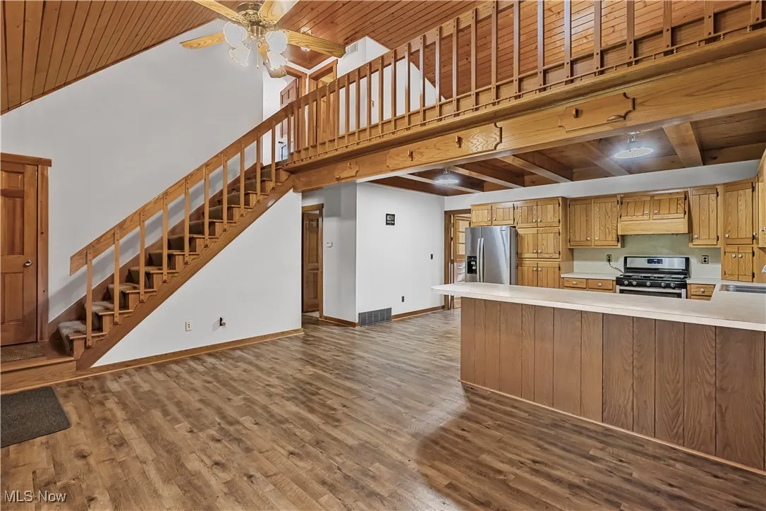 Kitchen with light countertops, a high ceiling, stainless steel appliances, dark wood finished floors, and wooden ceiling