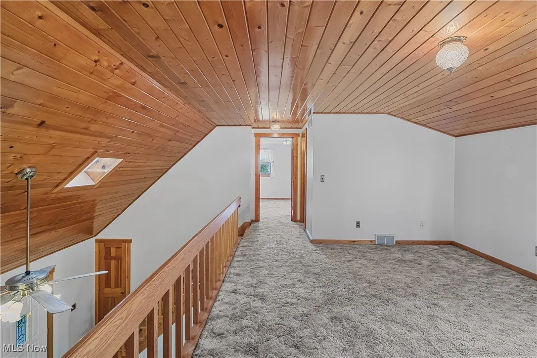 Bonus room featuring wooden ceiling, vaulted ceiling, carpet flooring, and a skylight