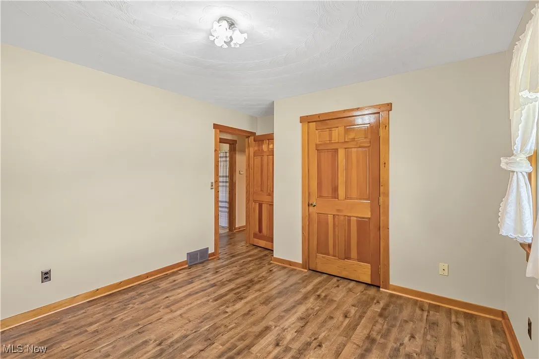 Unfurnished bedroom featuring wood finished floors and baseboards