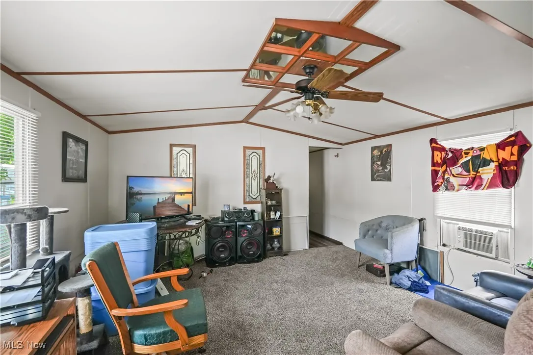 Carpeted living room featuring healthy amount of natural light, lofted ceiling, a ceiling fan, and crown molding
