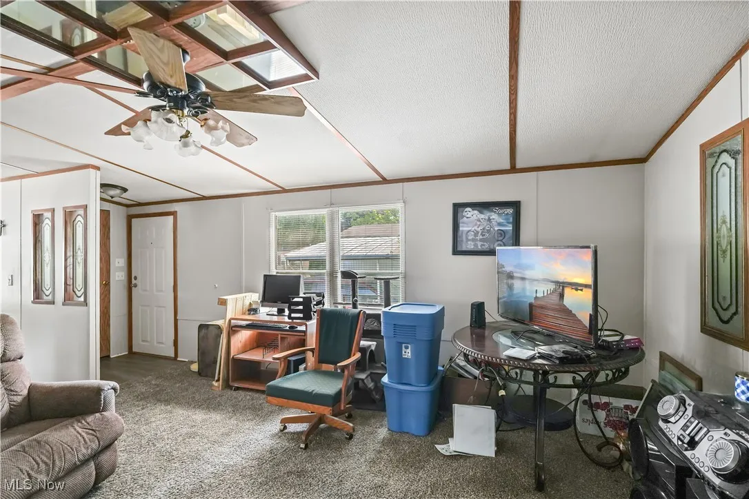 Carpeted office space with a textured ceiling, crown molding, and ceiling fan