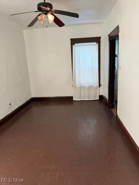 Empty room featuring dark wood-style flooring and a ceiling fan