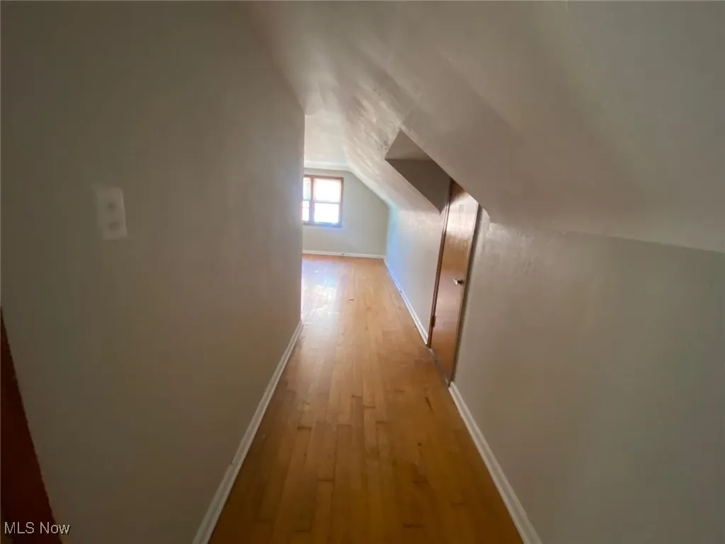 Corridor featuring light wood finished floors and vaulted ceiling