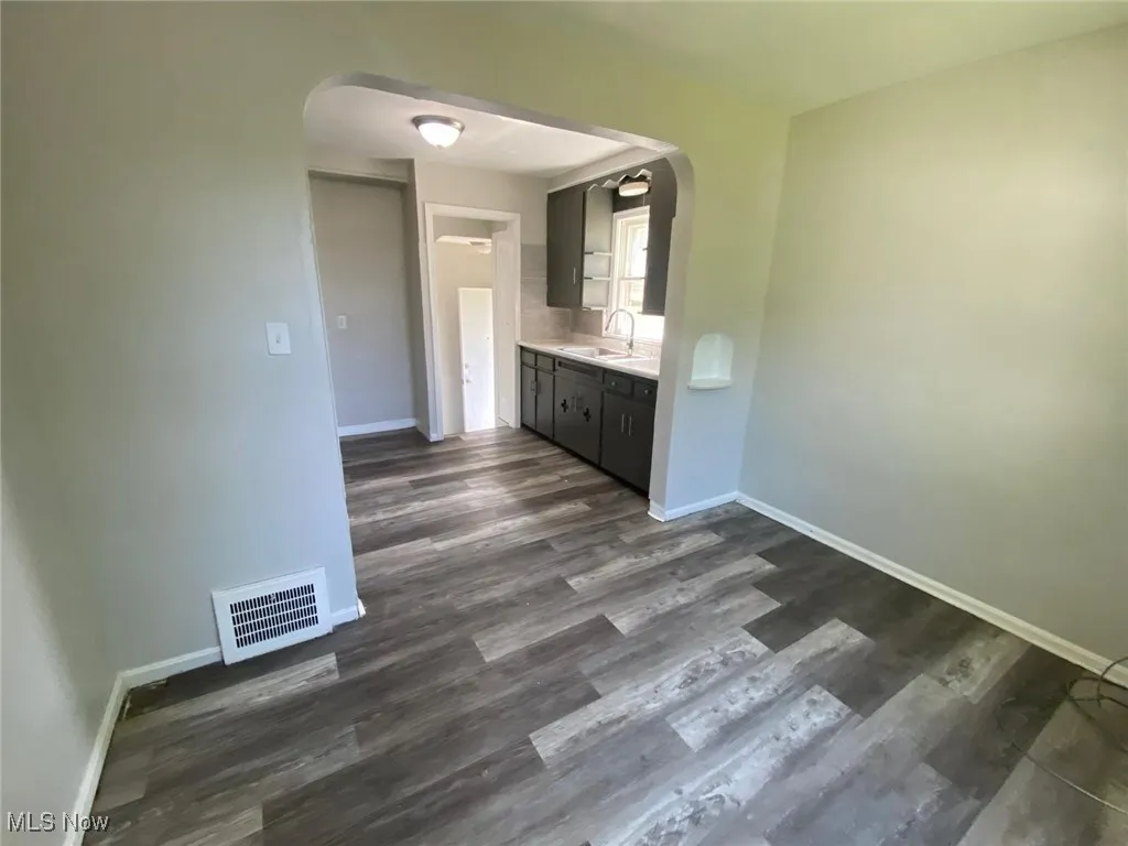 Unfurnished dining area with dark wood finished floors and arched walkways