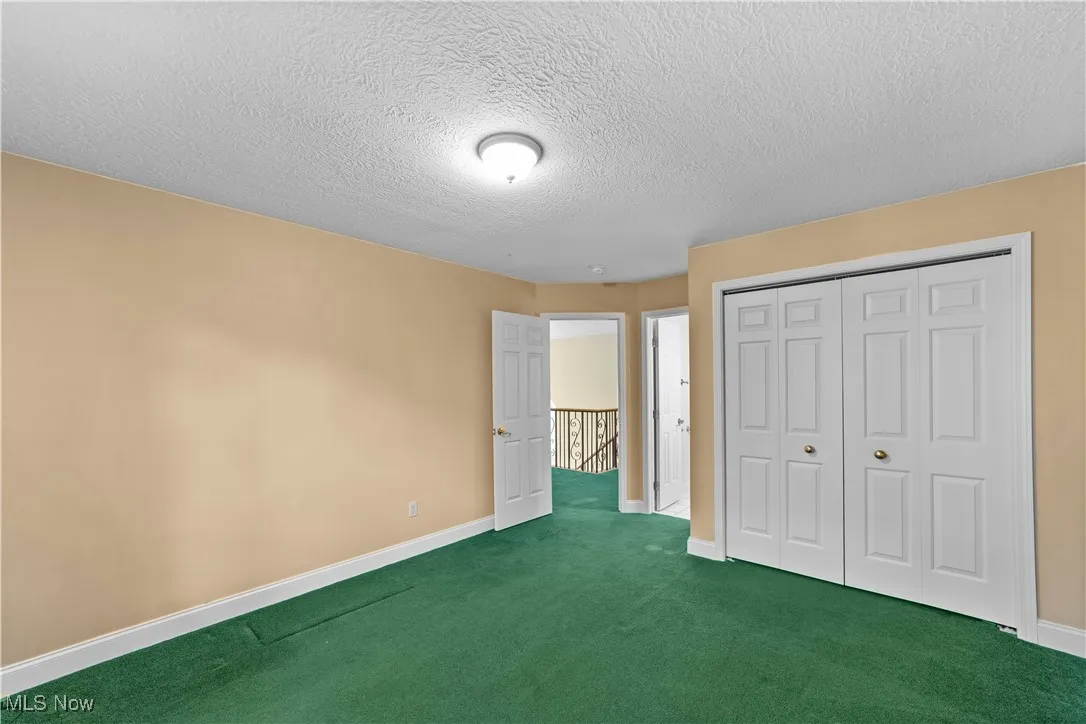 Unfurnished bedroom featuring carpet flooring, a textured ceiling, and a closet