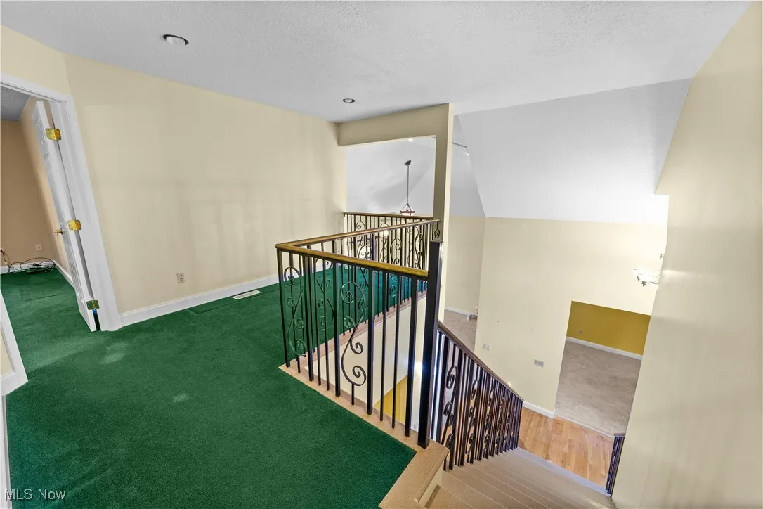 Staircase with carpet flooring, a textured ceiling, and lofted ceiling