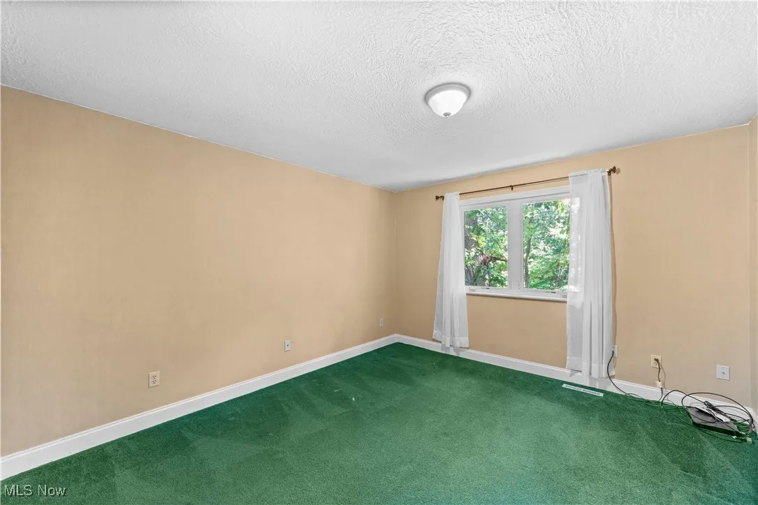 Carpeted empty room featuring baseboards and a textured ceiling