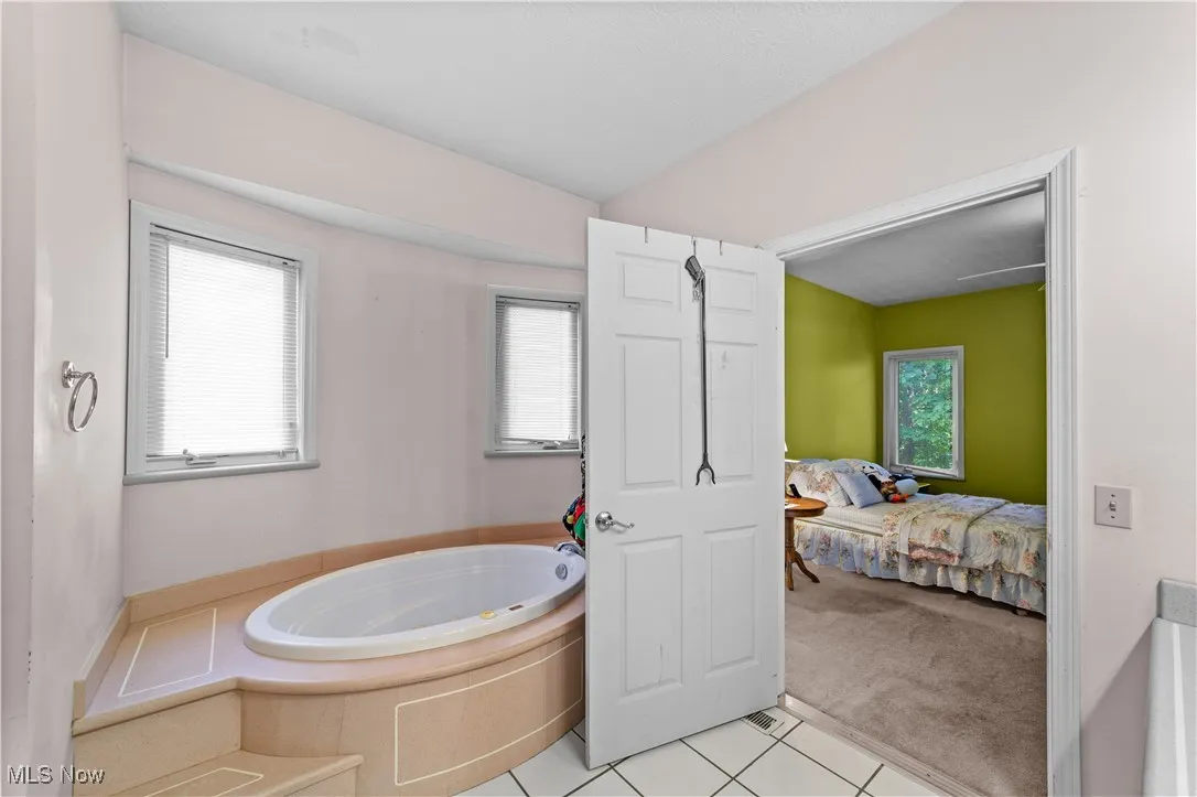 Full bathroom featuring light tile patterned floors, a bath, and connected bathroom