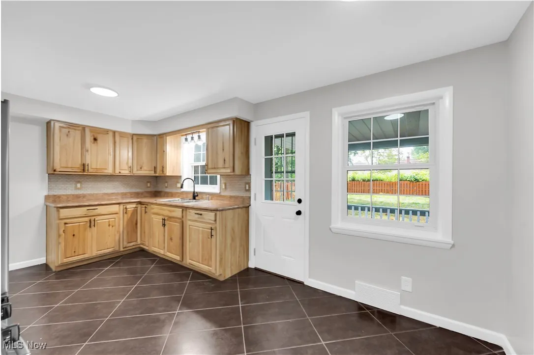 Kitchen featuring light brown cabinets, dark tile patterned floors, light countertops, backsplash, and recessed lighting